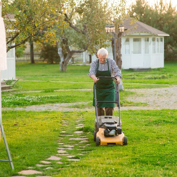 elderly man mowing lawn